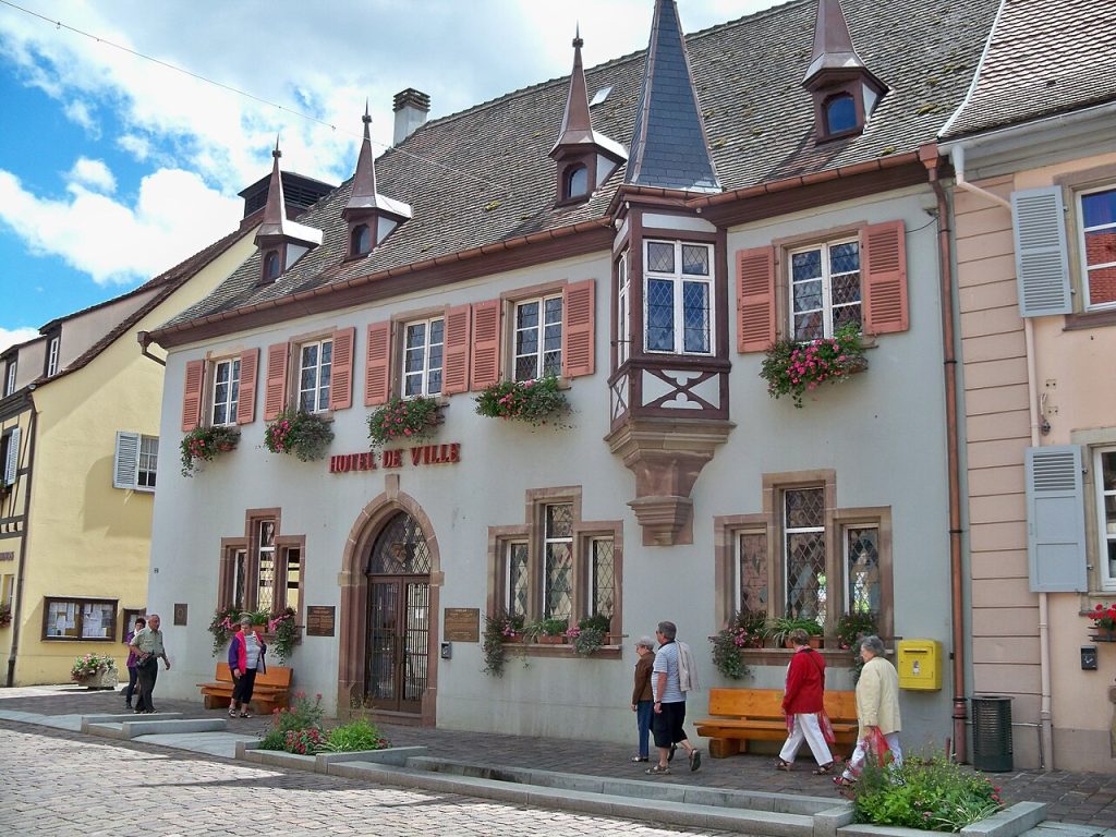 The flower-decked town hall with painted shutters