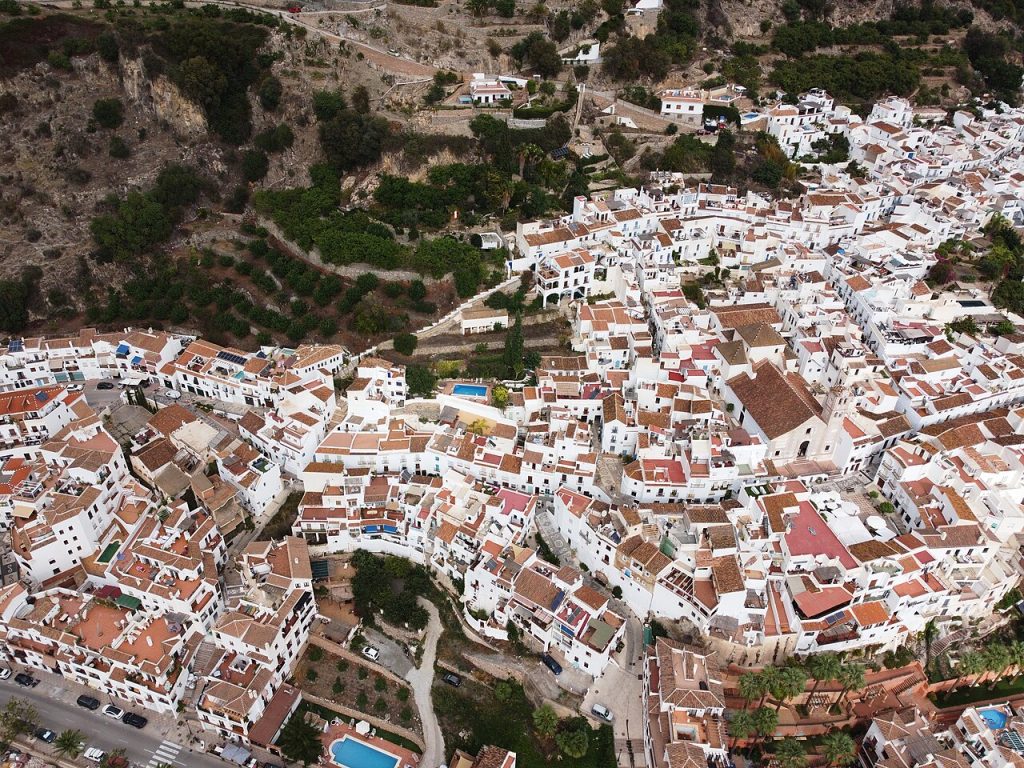 Aerial view of white houses and red roofs spread across the hillside