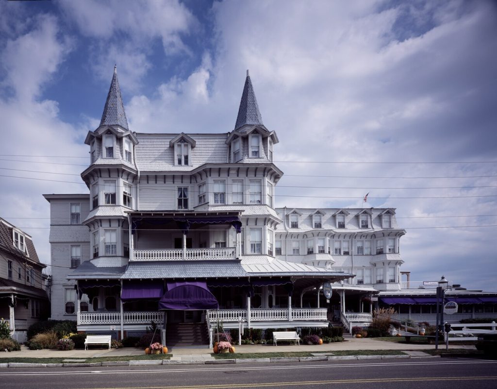 A grand white Victorian home with towers and porches