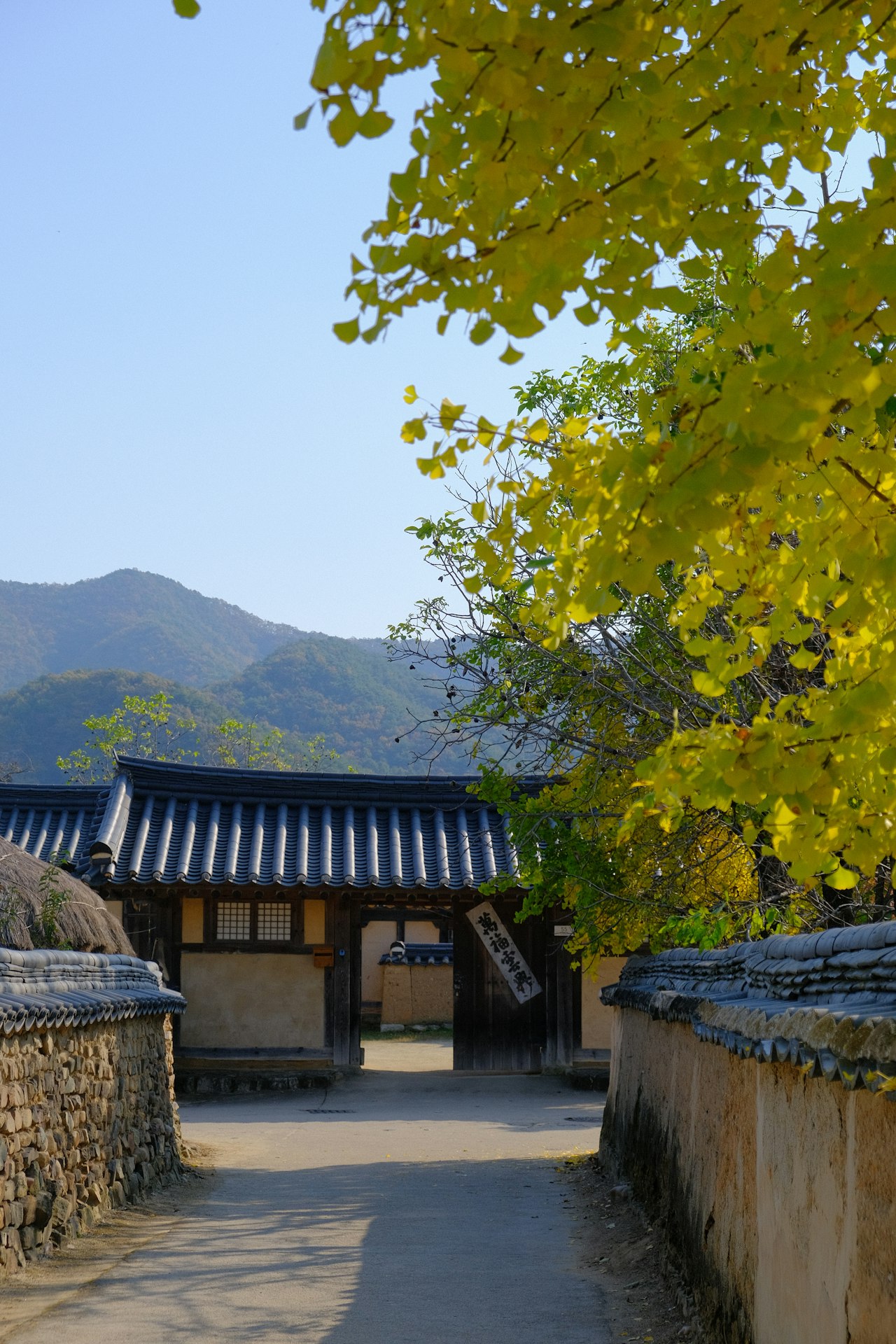 Path leading to a traditional building with hills behind