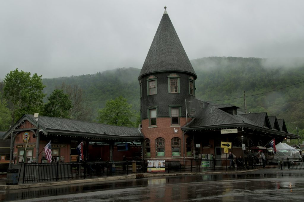 A brick train station with a tall spire below misty mountains in Jim Thorpe