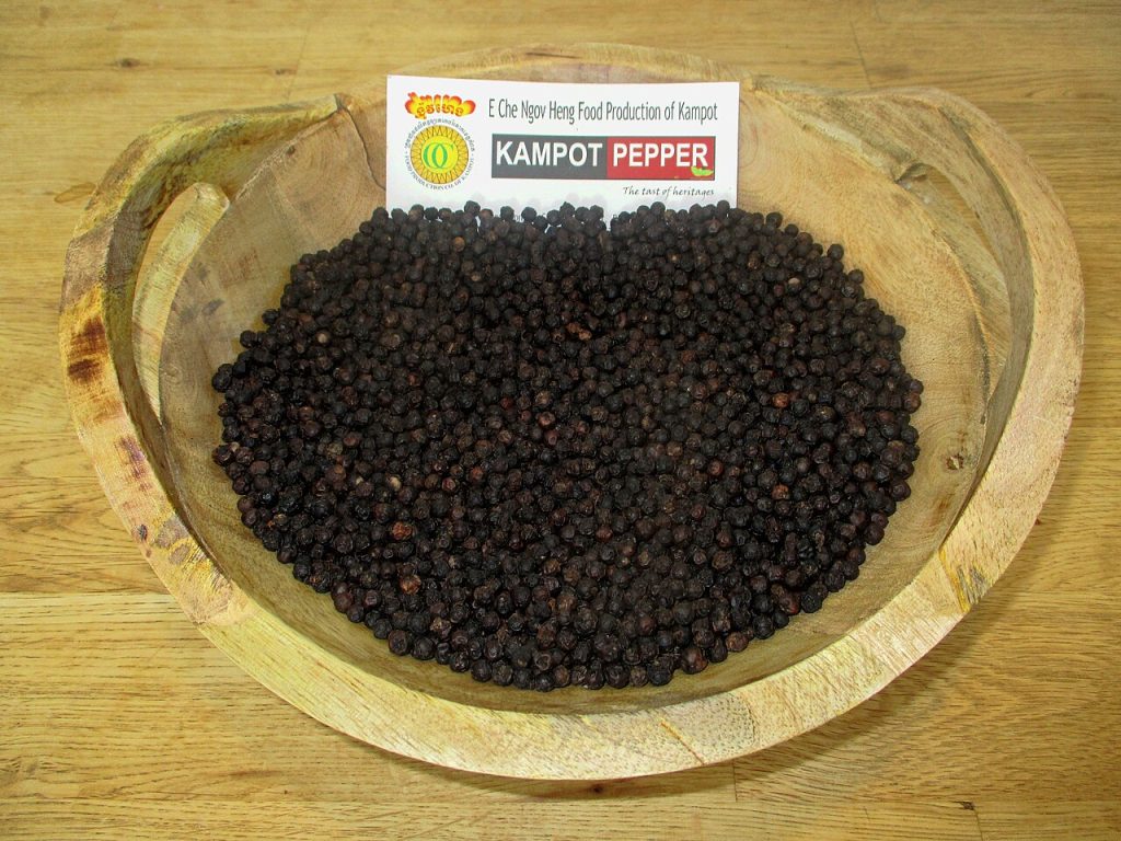 Black peppercorns in a carved wooden bowl
