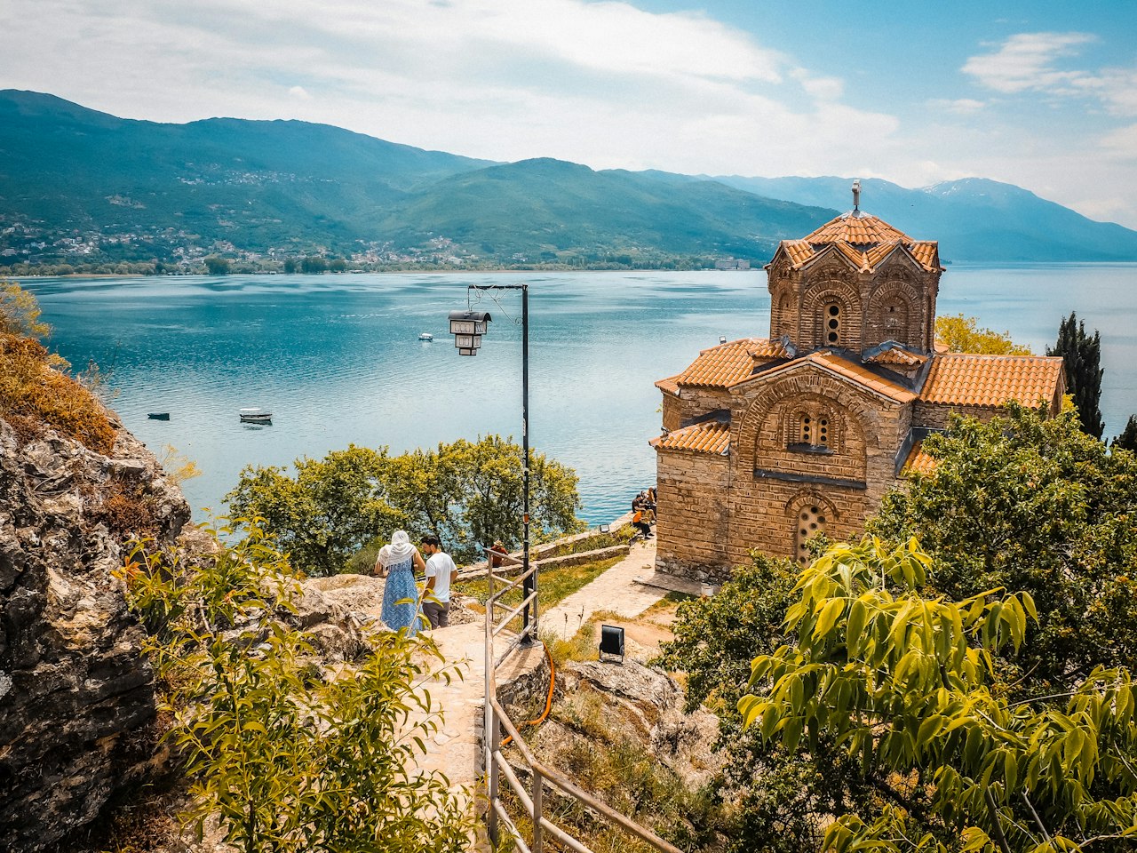 People walking up a hillside path beside the lake