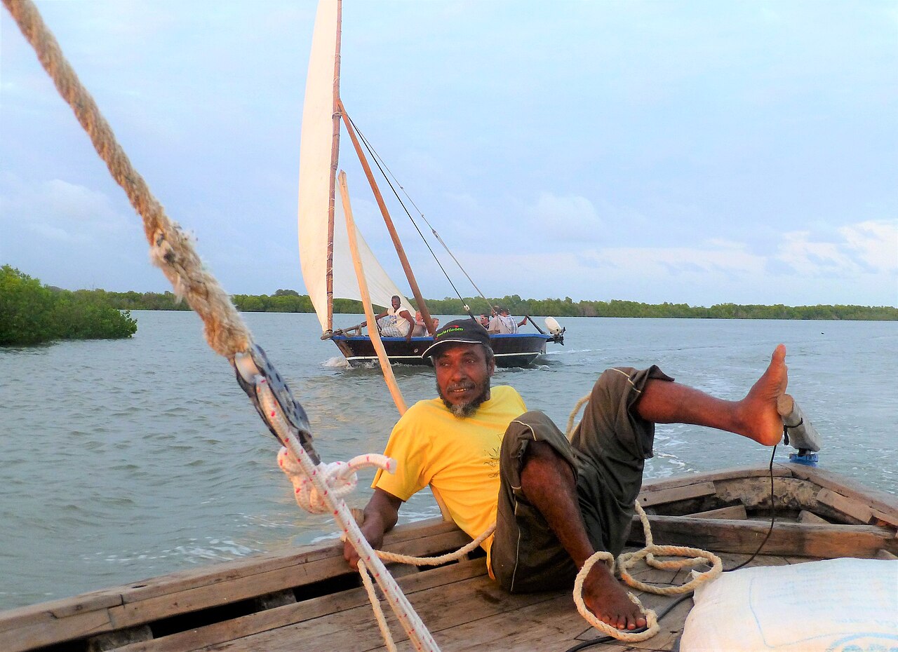 Traditional dhow sailing past the waterfront of Lamu Old Town in Kenya