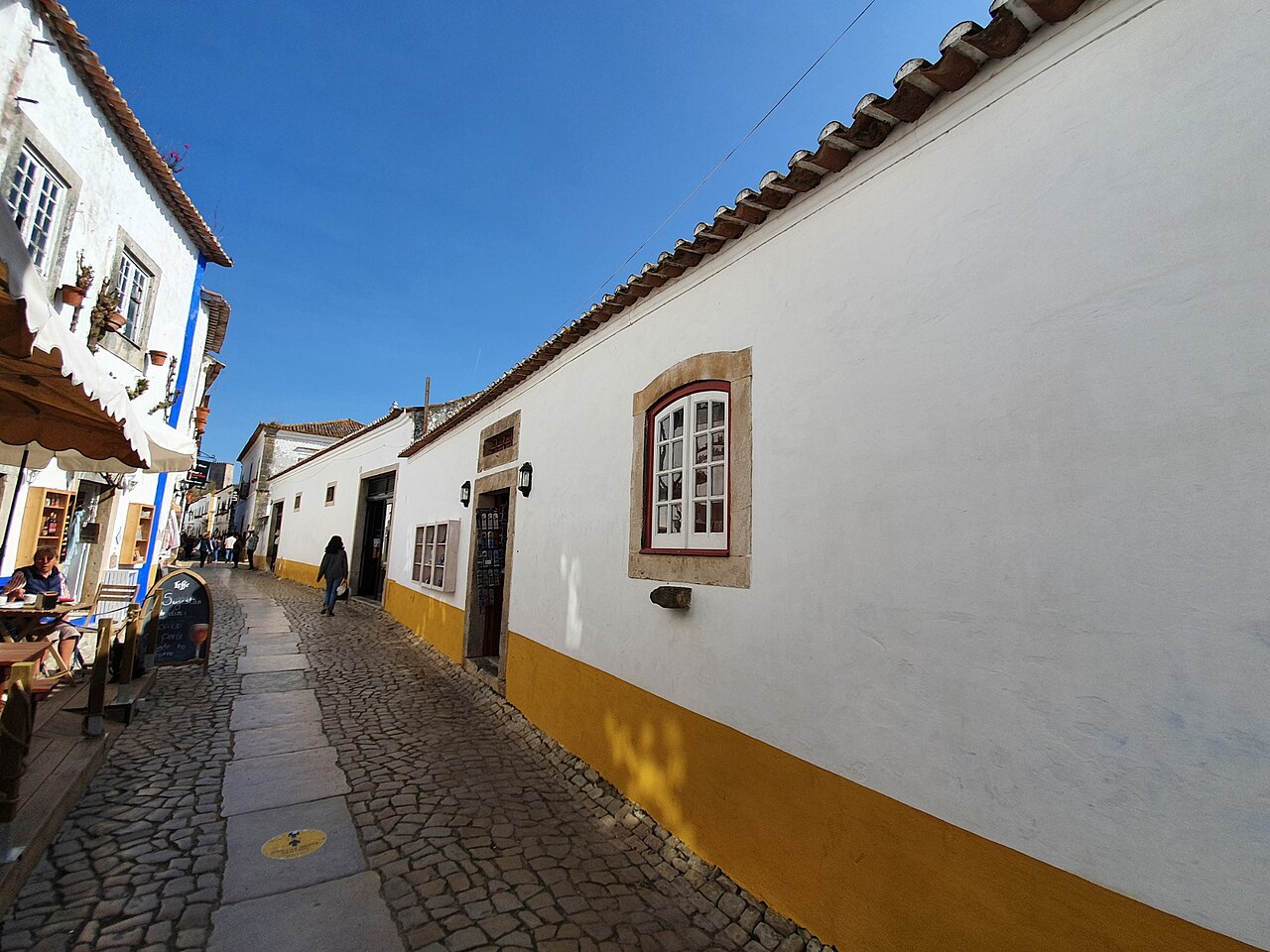 Whitewashed houses with blue and yellow trim along Rua Direita in Óbidos