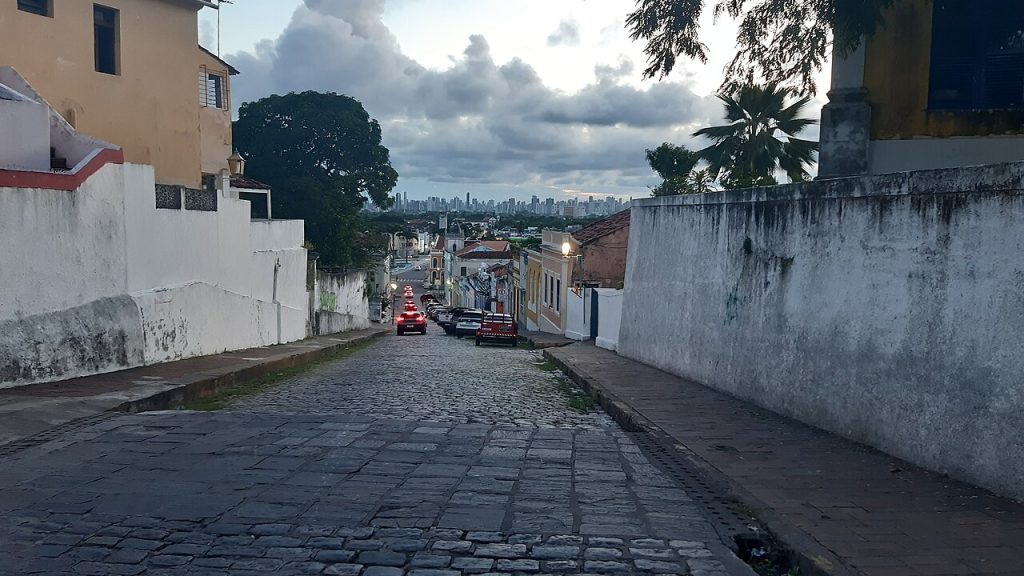 A sloping cobbled street lined with colonial houses