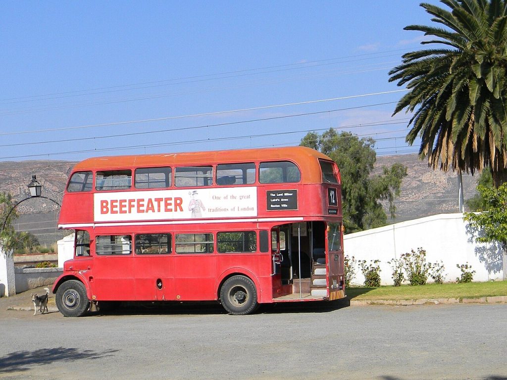 A red London double-decker bus parked in a Karoo village