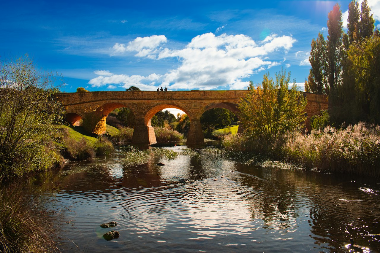 Stone bridge over a calm river under a blue sky