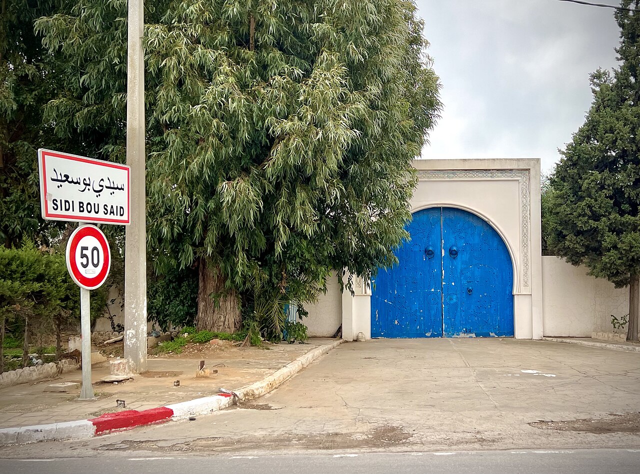 Ornate blue studded doors in a whitewashed gateway