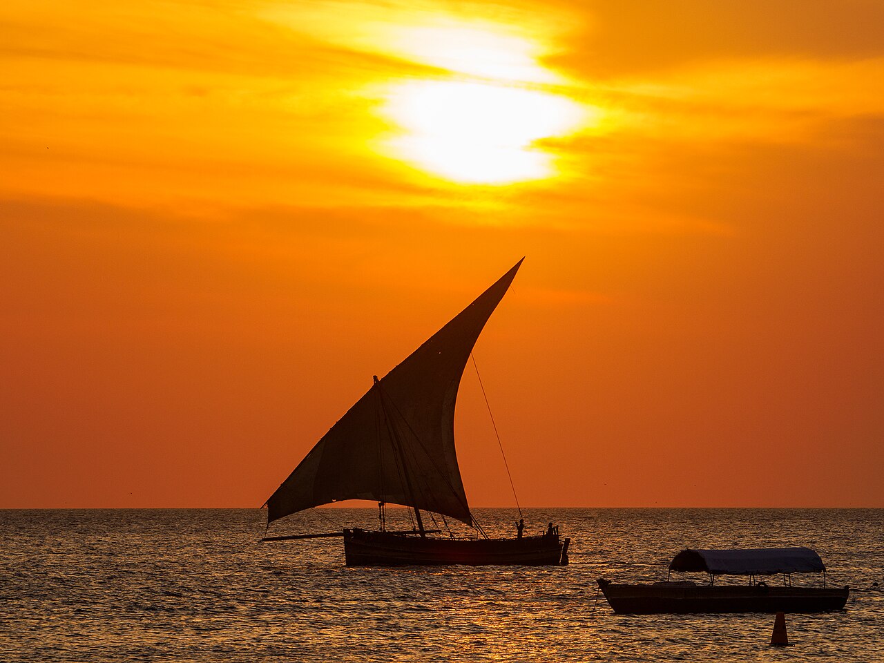 Dhow sailing at sunset off the seafront of Stone Town Zanzibar