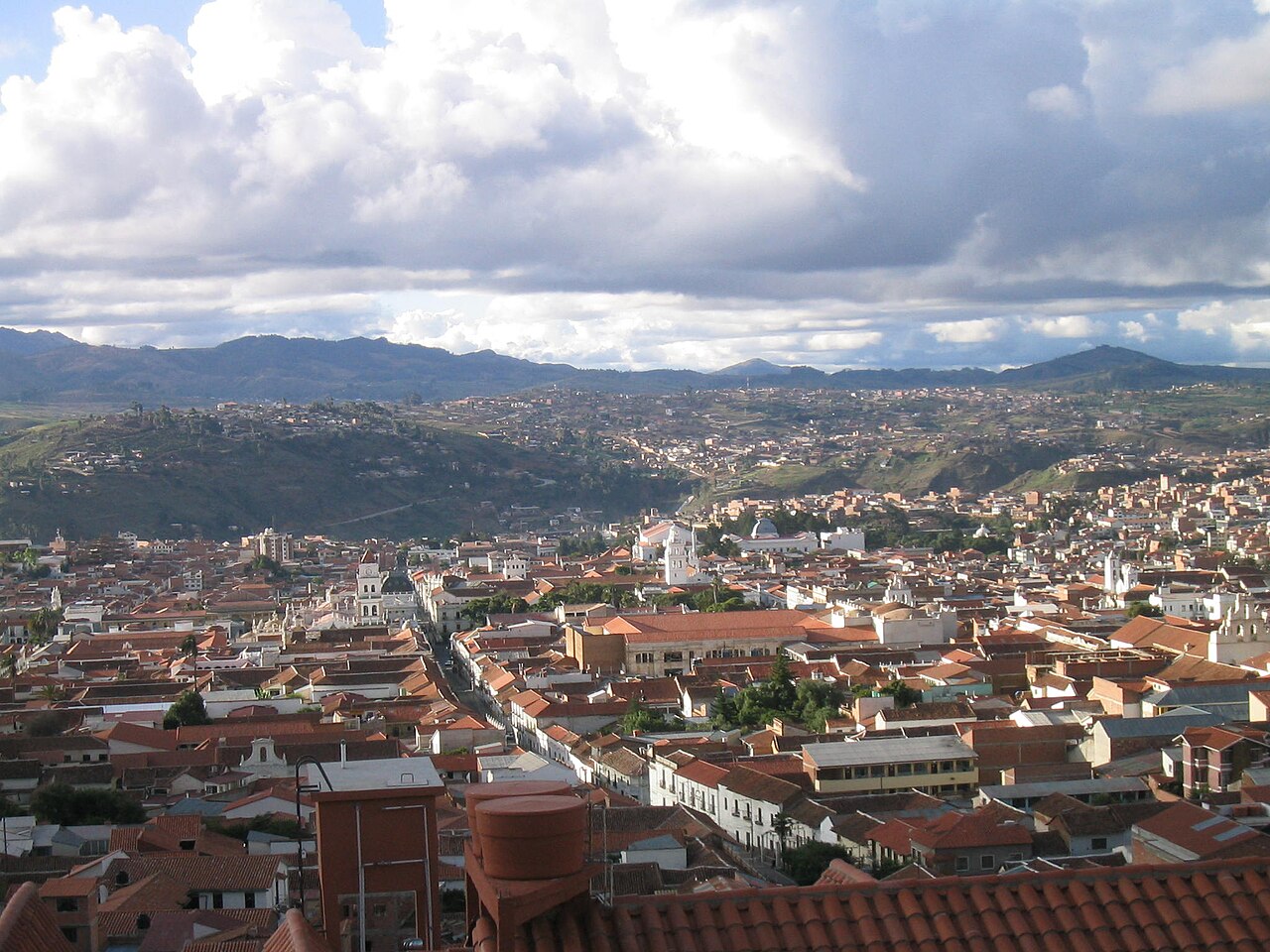 White colonial buildings and red roofs of Sucre Bolivia with mountains behind