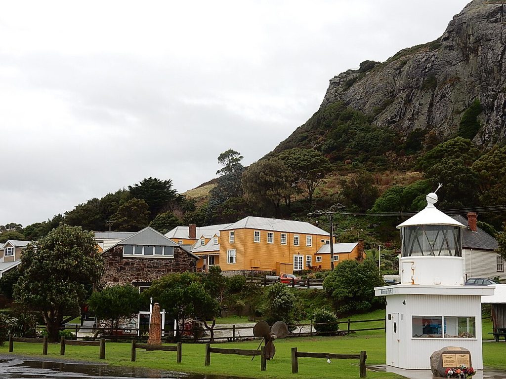 Houses and a lighthouse beneath the steep cliffs of The Nut