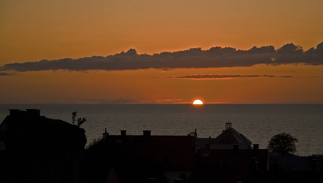 Sun setting over the Baltic Sea behind old town rooftops