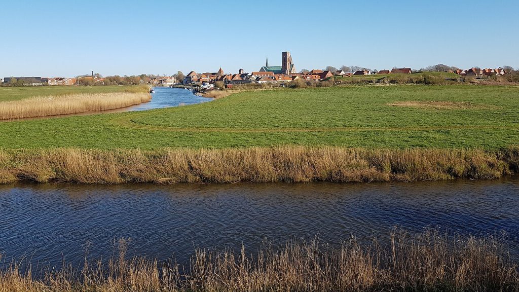 Flat marshland and river with the town on the horizon